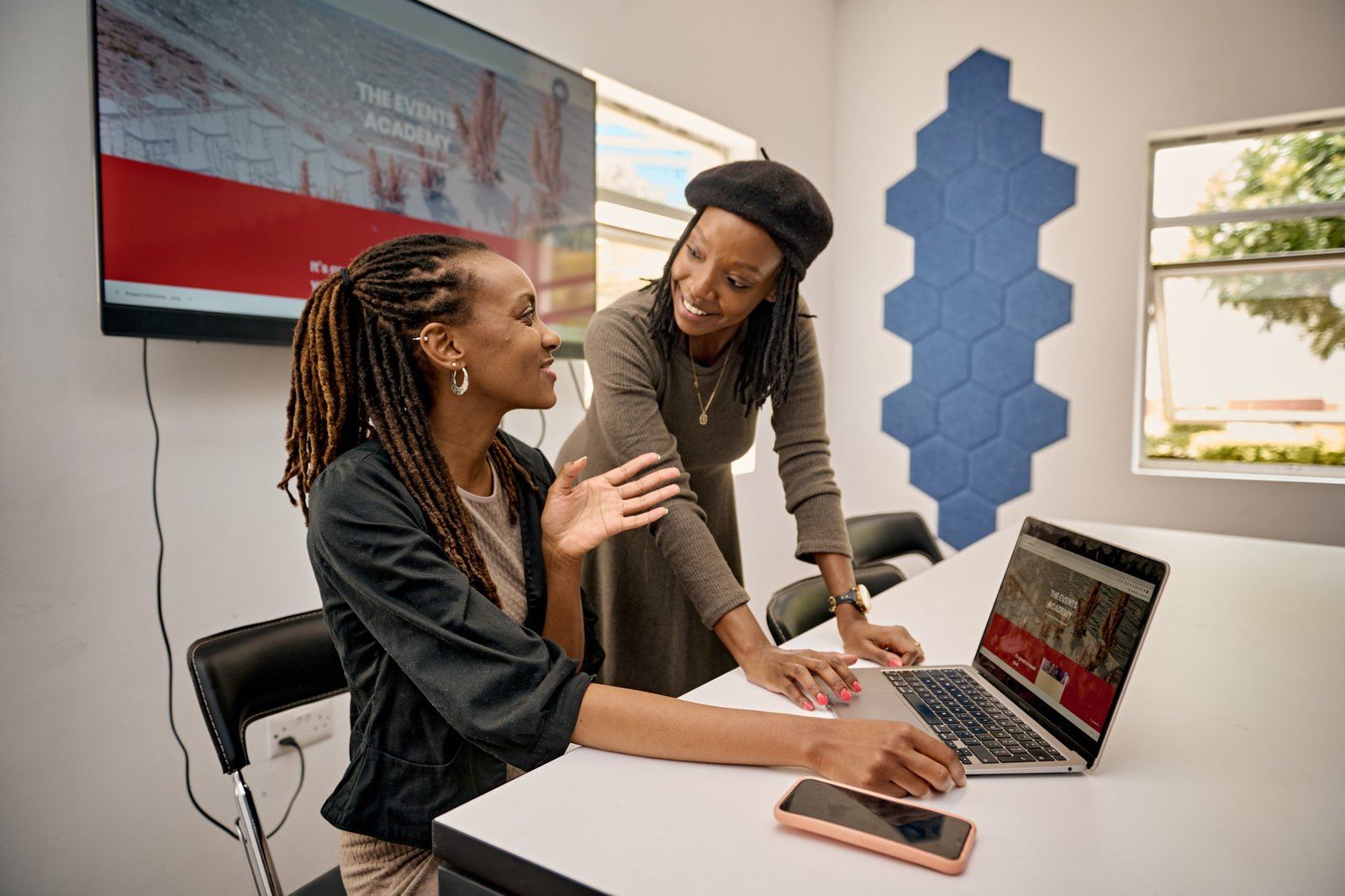 A trainer and a student reviewing work together on a laptop at The Events Academy
