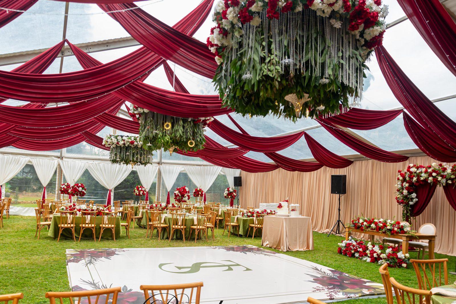 Event décor by Pearls and Roses: a marquee reception with red and ivory draping, hanging floral chandeliers and rose centrepieces